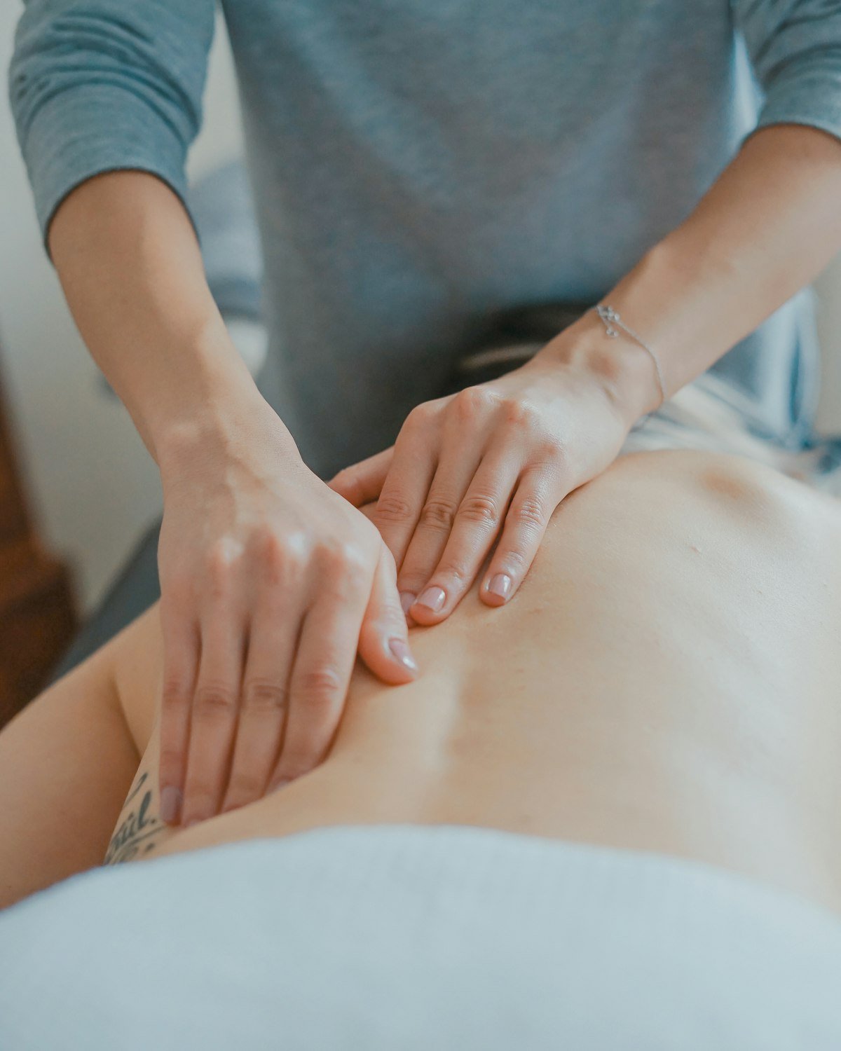 A registered physiotherapist applying hands-on treatment to a patient's lower back during a treatment session
