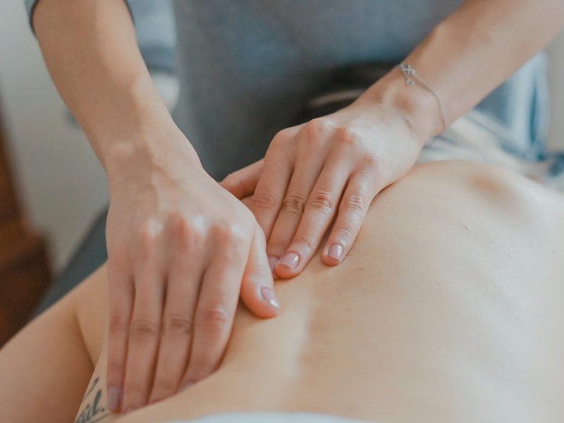 Therapist's hands performing soft tissue work on a patient's lower back